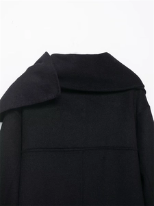 Detail of minimalist black wool jacket collar and shoulder stitching on a white background