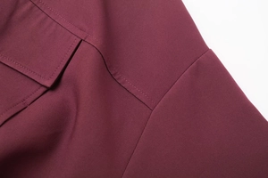 Détail d'un blouson aviateur bordeaux montrant les surpiqûres précises et la texture de poche