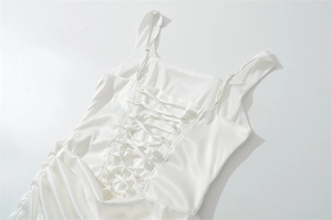 Detail of white satin dress featuring cross-strap lace-up back and adjustable straps