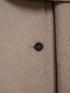 Close-up of the textured brown wool fabric and a black round button on the sleeve