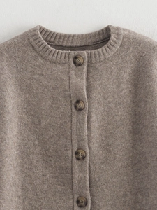 Close-up of knit cardigan featuring tortoiseshell buttons and round neckline texture