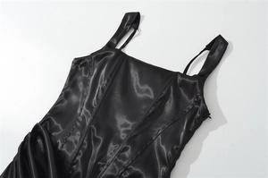Detail of black satin corset dress featuring adjustable straps and structured boning seams