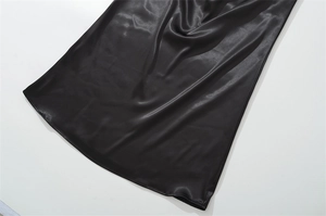 Detail of black satin dress hem showing high-gloss fabric texture and elegant drape