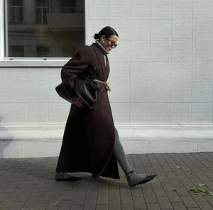 Dynamische Seitenansicht eines langen dunkelbraunen Wollmantels mit Revers im Streetstyle