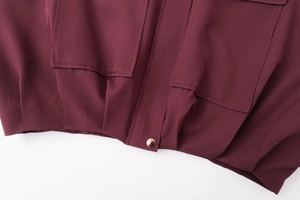 Détail de la veste aviateur bordeaux avec poches à rabat et bouton en métal or rose