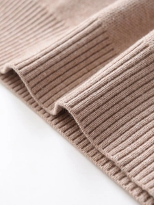 Detailed close-up of ribbed cuffs on beige knitted sweater set with soft wool texture