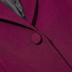 Detailed close-up of dark purple twill coat with fabric-covered button and black lining