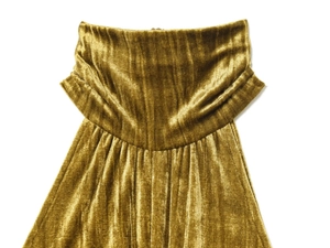 Dettaglio dell'abito in velluto giallo senape con elegante scollo a pieghe e increspature