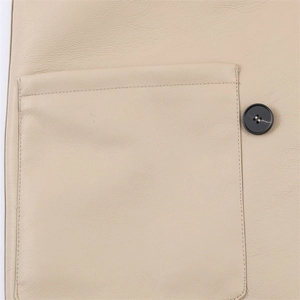 Detailed close-up of premium beige leather jacket featuring a pocket and black button