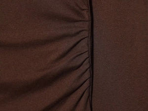 Gros plan détaillé sur un tissu en maille marron foncé avec élégants fronces et plis