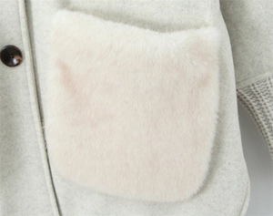 Detail of light gray knit jacket featuring soft faux fur pocket and marbled button