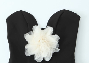 Close-up of a large white 3D mesh flower detail on a black tube top with layered petals