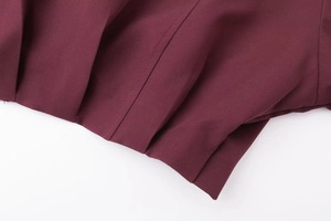 Détail du tissu bordeaux plissé montrant les coutures précises et la texture lisse