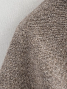 Detailed macro shot of premium tan knit sweater fabric with soft wool texture and fine stitching