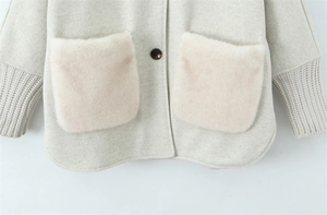Detail of oatmeal jacket featuring soft pink faux fur pockets and rib-knit cuffs