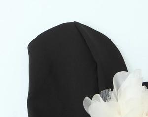 Detail shot of black knitted tube top with a white mesh 3D flower decoration