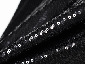 Vue détaillée du tissu à paillettes noires avec texture et reflets brillants