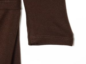 Détail d'un t-shirt en maille marron foncé montrant la couture double aiguille aux poignets