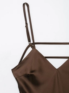 Macro shot of dark brown satin dress detail showing silk texture and thin shoulder straps