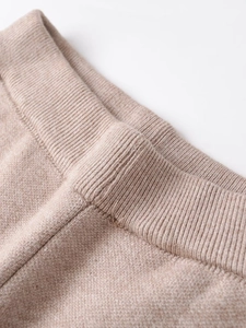Detailed close-up of high-quality oatmeal knit fabric with ribbed cuffs and soft texture