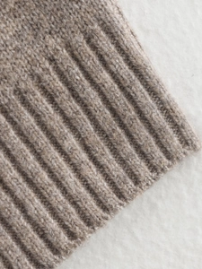 Close-up of the beige knit cardigan showing premium soft wool texture and ribbed edges