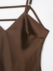 Detail shot of a dark brown satin slip dress showing silky texture and thin straps