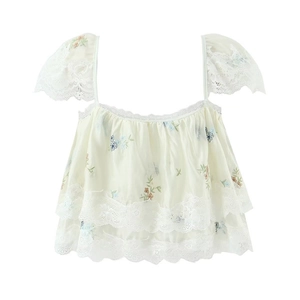Detailed view of floral embroidery and layered lace hem on creamy white chiffon top