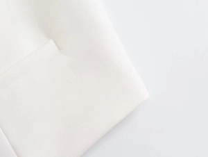 Vue détaillée de la texture du tissu sergé blanc crème et des coutures de la poche du costume