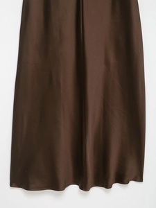Detail of chocolate satin dress fabric showing smooth texture and metallic sheen