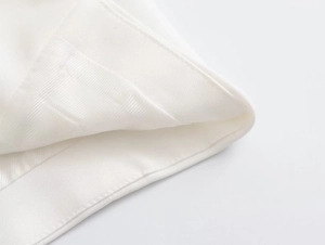Gros plan détaillé montrant les coutures de qualité et la doublure en satin du pantalon blanc