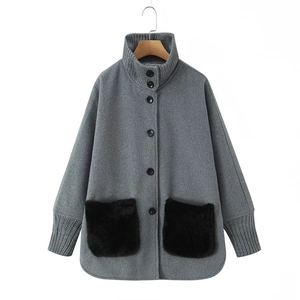 Detail of grey winter coat with high stand collar and large black faux fur pockets