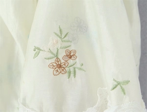 Macro detail of intricate floral embroidery and white lace trim on the white fabric