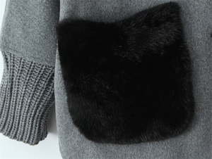 Detail of grey winter jacket featuring plush black pocket and ribbed knit cuffs