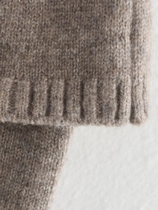 Close-up of melange brown knit sweater showing soft wool texture and ribbed cuff detail