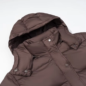 Detail view of the drawstring hooded collar and snap buttons on a brown puffer jacket