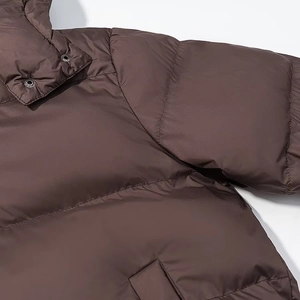 Close-up of brown quilted jacket showing stand collar, metal snaps and fine fabric texture