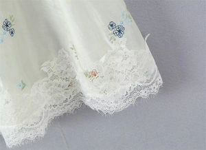 Detailed close-up of floral embroidery and delicate eyelash lace on a white skirt hem
