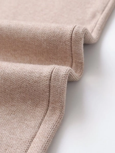 Macro detail of camel cashmere knit fabric texture and fine hem stitching on the sweater