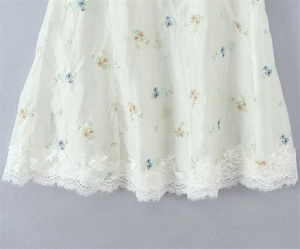 Detailed macro view of embroidered floral patterns and delicate eyelash lace trim on the hem