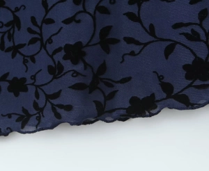Detail of navy mesh fabric featuring black flocked floral pattern and lettuce hem design