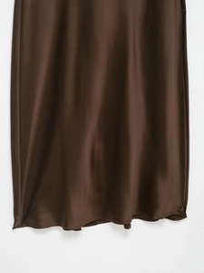Detailed view of brown satin dress hem showcasing smooth texture and fine stitching