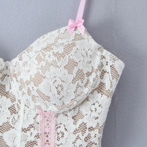 Detail of white floral lace camisole featuring pink straps and small decorative bows