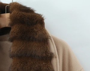 Close-up of fluffy faux fur collar and wool blend fabric on a beige winter coat for women