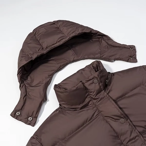 Detail view of a dark brown puffer coat featuring a detachable hood and snap buttons