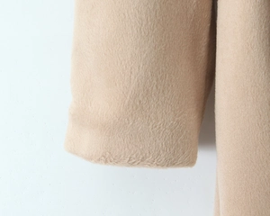 Close-up of thick beige faux fur texture on the sleeve cuff of a winter wool coat