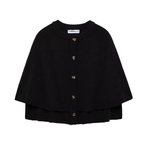 Detail view of round neck knit poncho showing black buttons and brand neck label