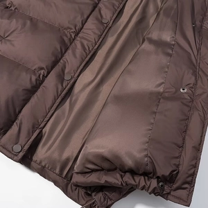 Detail of dark brown quilted puffer jacket with smooth satin finish and metal snap buttons