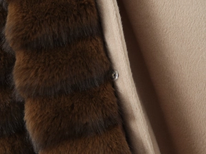 Detailed macro shot of dark brown faux fur texture and a transparent button on the wool coat