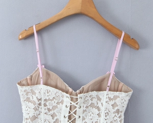 Close-up of white floral lace top with pink straps and front lace-up detail