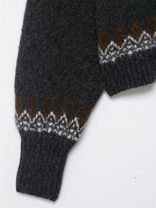 Gros plan du pull en laine gris foncé avec des motifs Fair Isle rétro sur les poignets